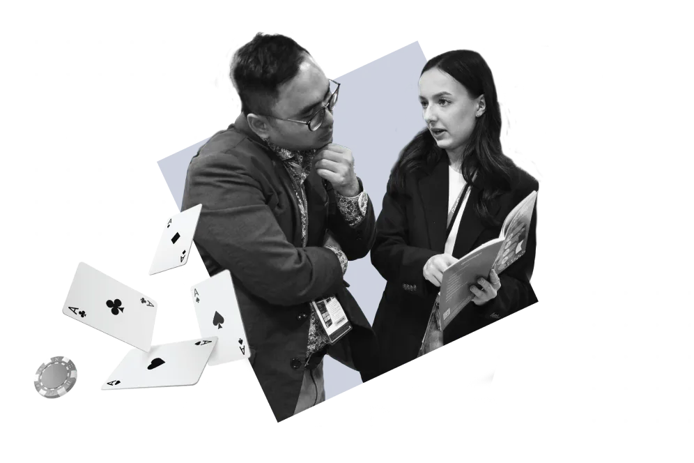 Two people in business attire talking, with playing cards in the foreground